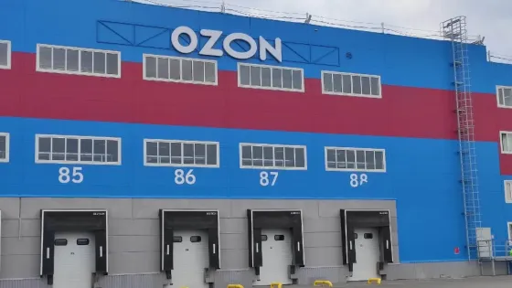 Команда сотрудников на собрании за столом с компьютерами и экраном для видеосвязи