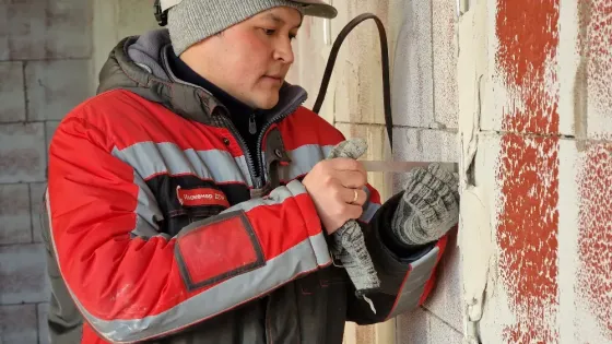 Рабочий кладет стеновые блоки на строительном объекте