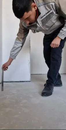 Рабочий использует уровень для проверки вертикальности стены