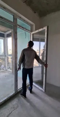 Рабочий использует уровень для проверки вертикальности стены