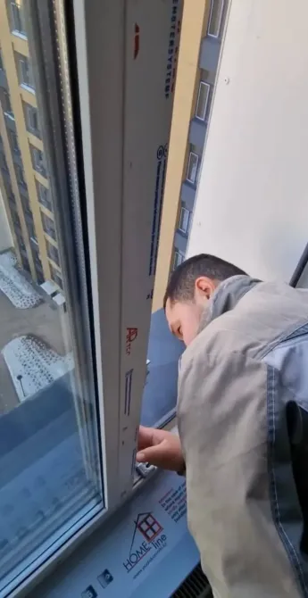 Рабочий устанавливает окно в строительном объекте