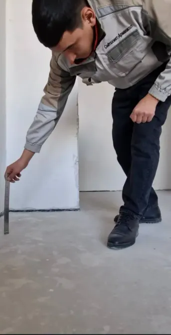 Рабочий измеряет длину с помощью строительной линейки