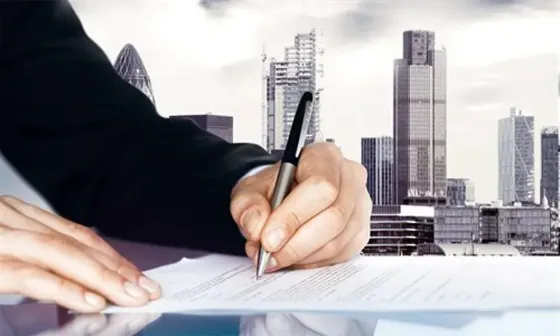 Компьютер, строительная каска, измерительная лента и чертежи на столе