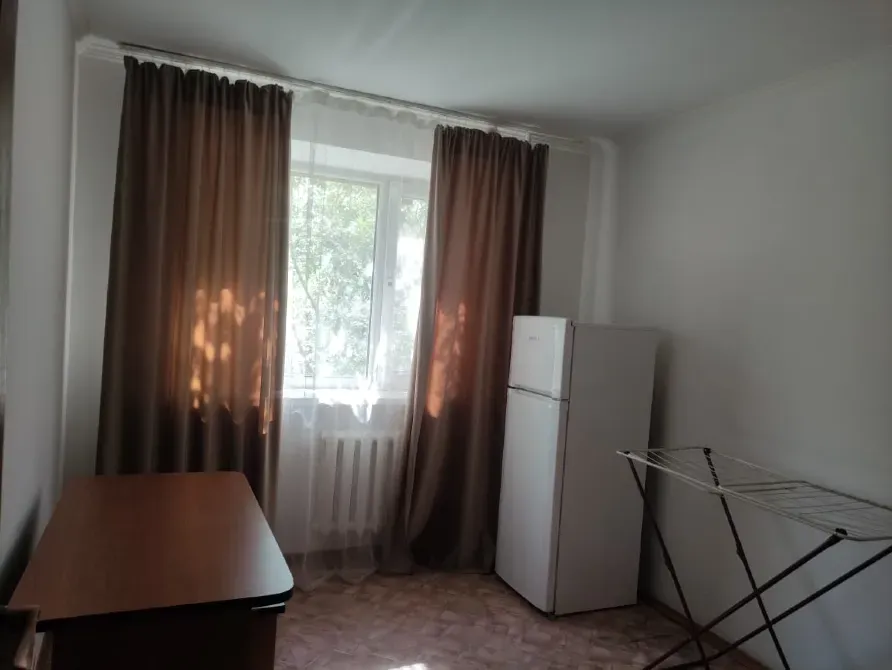 Комната с холодильником, шкафом и сушилкой для одежды, освещенная солнечными лучами