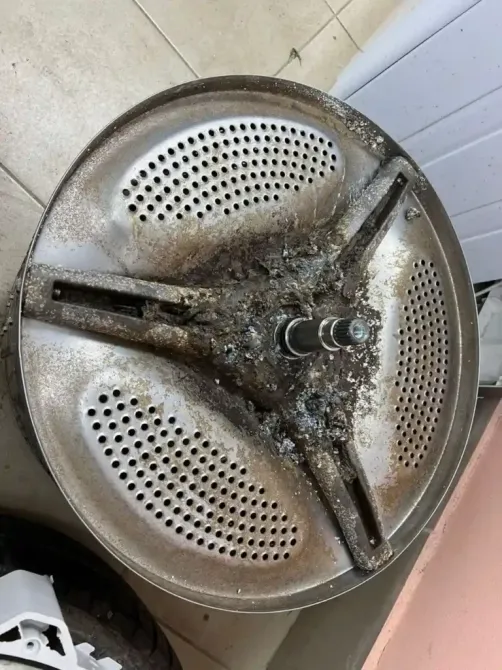 Поврежденный барабан стиральной машины с остатками грязи