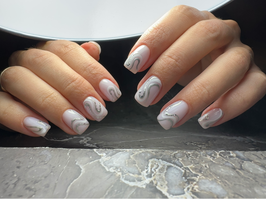 Ногти с украшениями и волнообразными линиями на светлом фоне