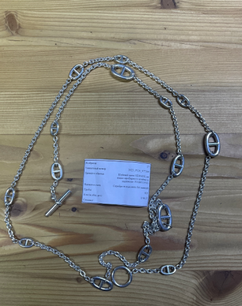 Длинное серебряное ожерелье с овальными звеньями и зажимом на деревянном столе