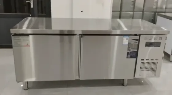 Металлический холодильный стол с двумя дверцами и гладкой поверхностью из нержавеющей стали, установленный на ножках