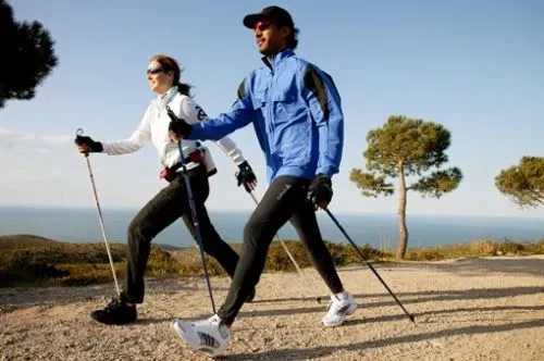 Силуэт человека, занимающегося скандинавской ходьбой на фоне заката