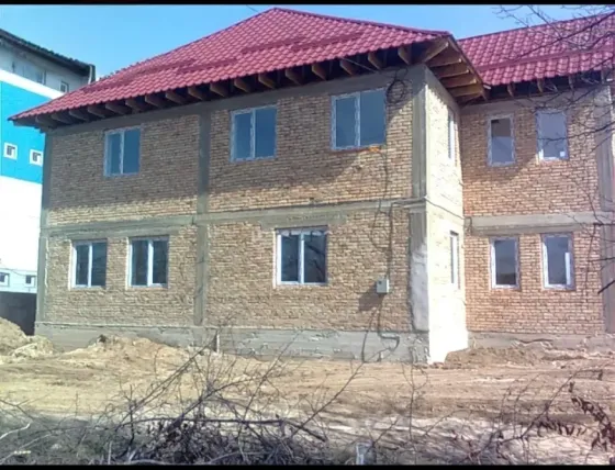 Құрылыс үстіндегі кірпішпен әрленген үй және қызыл шатыр