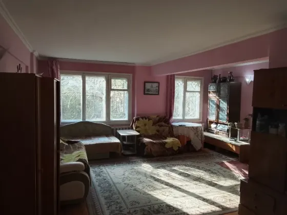 Розоватые қабырғалар мен ағаш едені бар коридор, күн сәулесімен жарықтандырылған