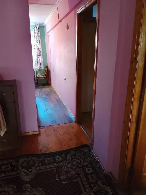 Розоватые қабырғалар мен ағаш едені бар коридор, күн сәулесімен жарықтандырылған