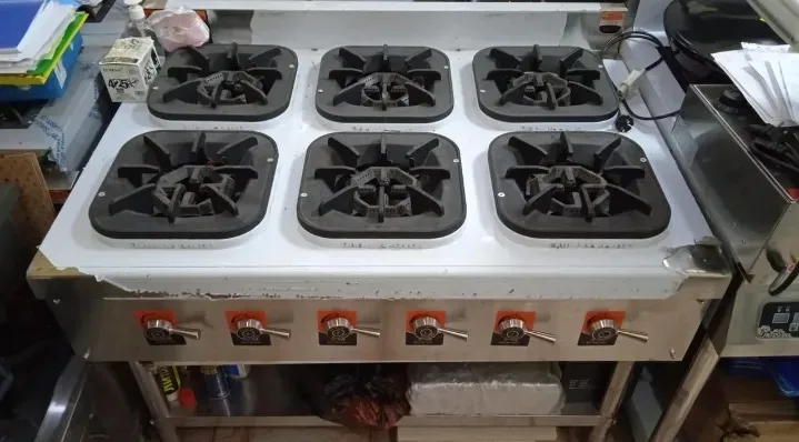 Плита с шестью конфорками и металлическим каркасом, используется в коммерческой кухне