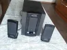 Microlab аудиосистема, екі колонка және сабвуфермен, үстелдің алдында матамен безендірілген.