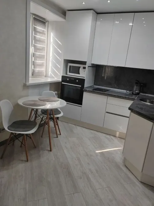 Современная кухня с белыми шкафами и столом на двоих