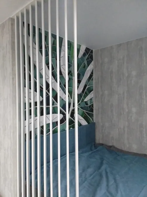 Зона сна с красивой мозаикой на стене и разделительной конструкцией