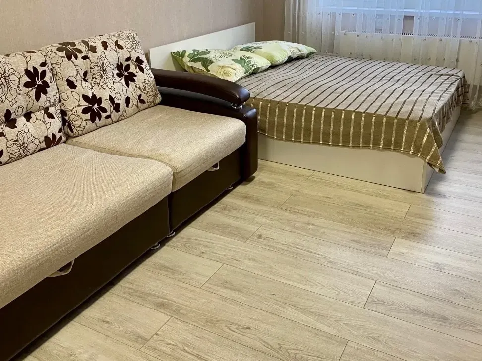 Уютты жатын бөлмесі диванмен және терезе жанындағы төсекпен