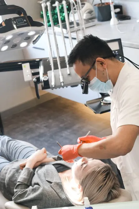 Стоматолог, обслуживающий пациента с защитным снаряжением