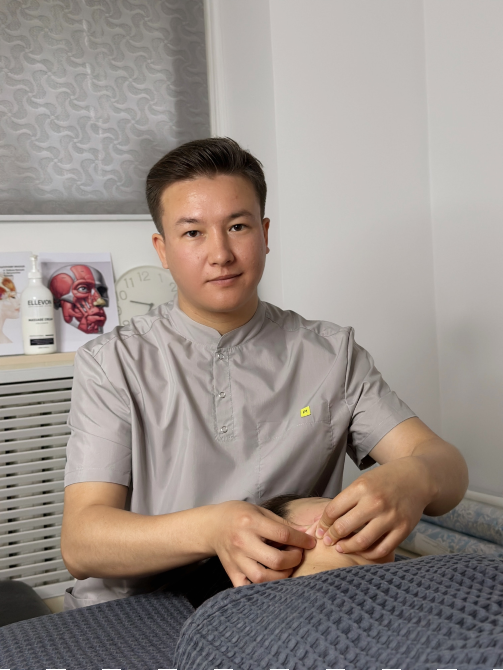 Мужчина в халате проводит процедуру на теле клиента в современном массажном кабинете