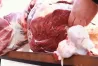 етке қойылған ет, оны бөлшектеуге жұмыс істеп жатқан қолдар