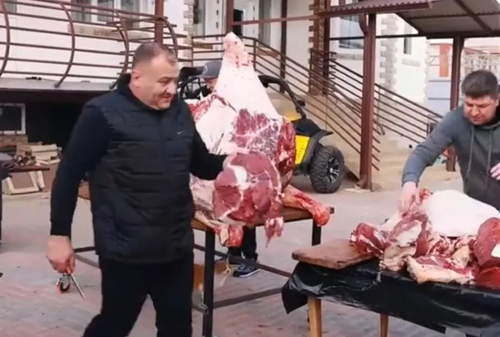 бір адам ет кесегін ұстап отыр, екіншісі таблицада етпен айналысып жатыр