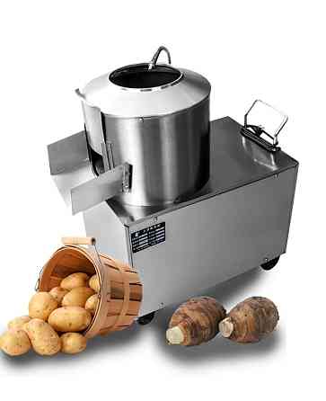 Картонка с картофелем и ямой, рядом с кухонным аппаратом для обработки овощей в металлическом корпусе