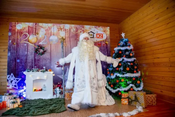 Дед Мороз с девочкой в белом платье на фоне новогодней елки