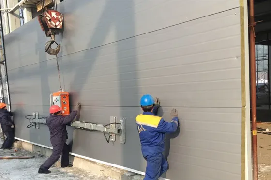 На заводе по производству сэндвич-панелей работники складывают панели в ряд на конвейере