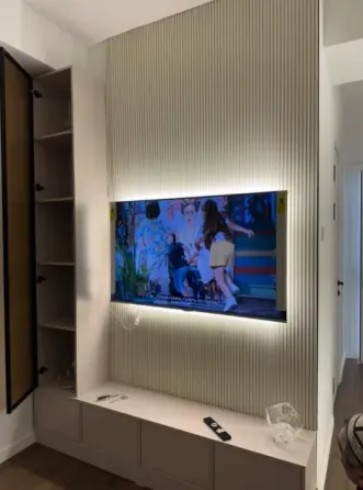 Современный интерьер с телевизором на стене и полками для книг