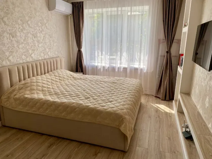 Современная спальня с светлым текстилем и большими окнами, создающими атмосферу уюта