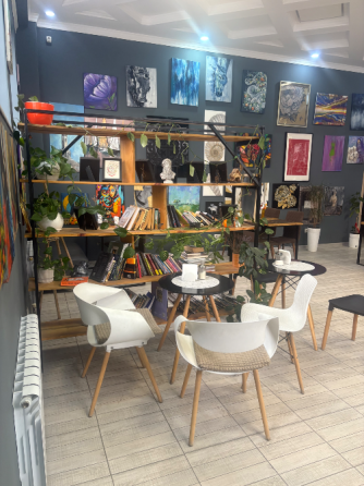 Кітапхана және қабырғаларында өнер туындылары бар кафе интерьері