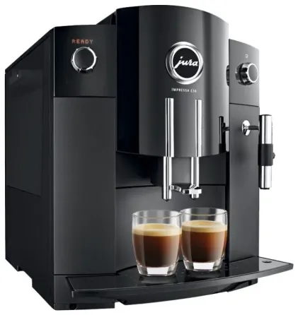 Кофемашина, готовящая кофе с паром, на фоне окна с зеленью