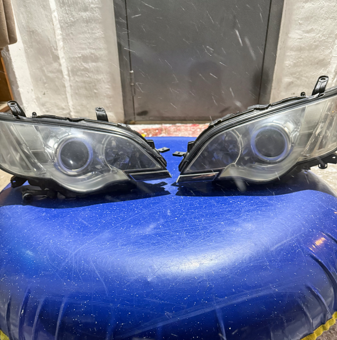 Екі автокөлік фарасы көк фонның жанында