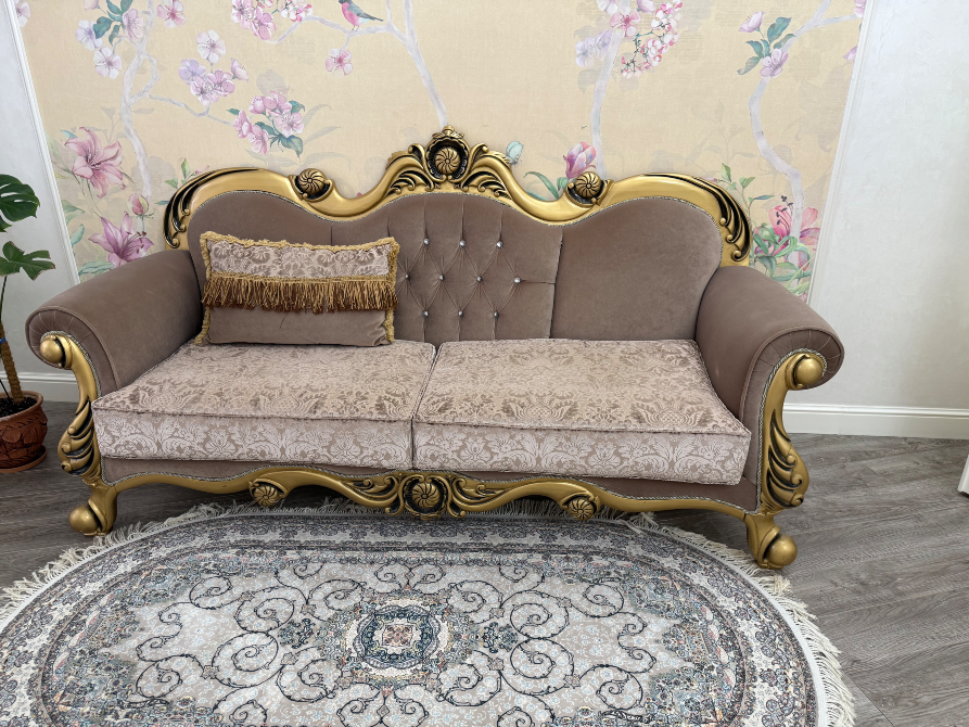 Дорогой диван с золотыми элементами и украшениями на спинке