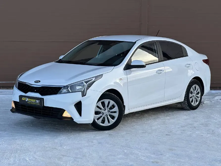 Белый седан Kia с современным дизайном на фоне снега