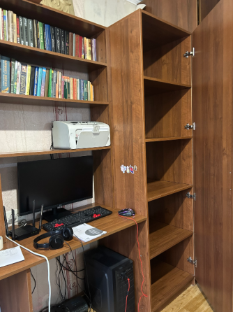 Ағаштан жасалған мебель және сөрелердегі кітаптармен кабинет