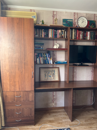 Ағаштан жасалған мебель және сөрелердегі кітаптармен кабинет