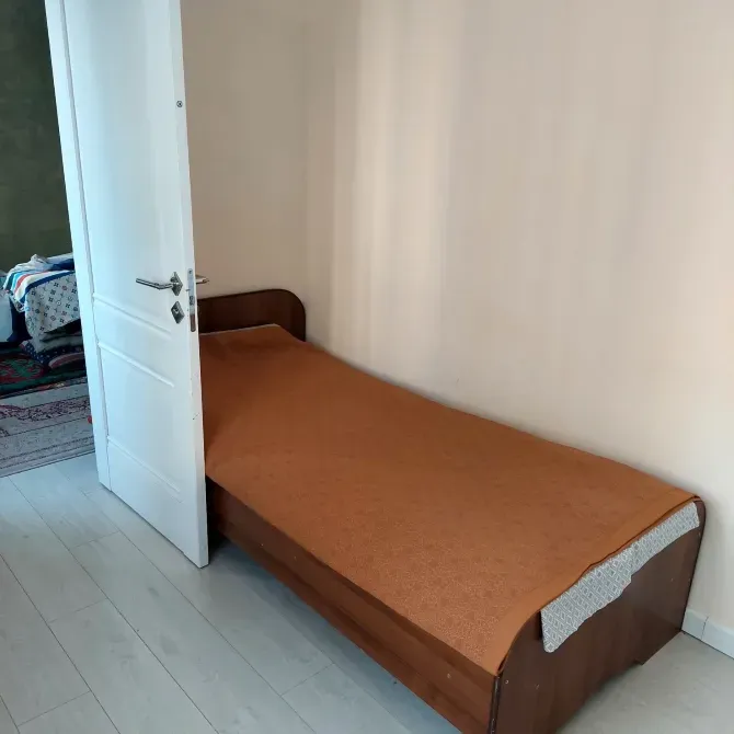 Кровать с оранжевым покрывалом в комнате с открытой дверью