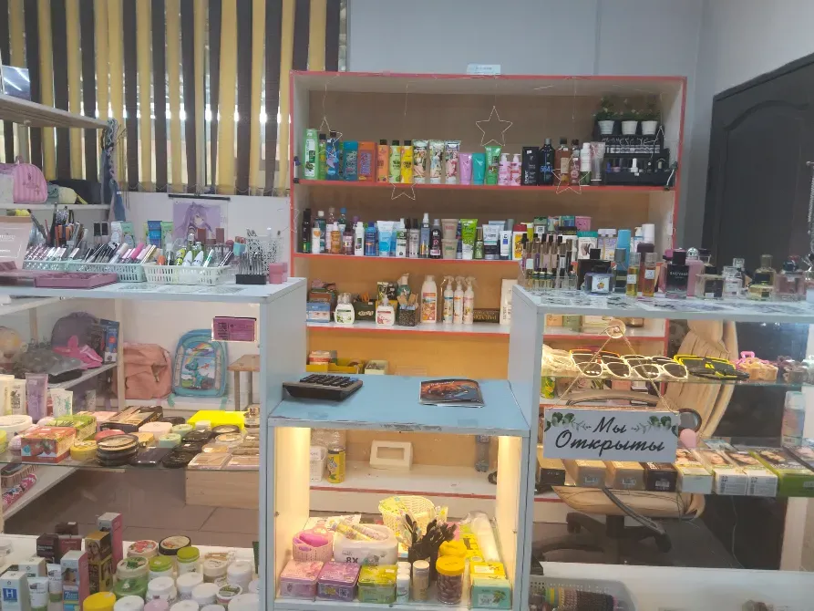 Косметикалық дүкеннің бұрышында теріні күтуге арналған тауарлармен және косметикамен толтырылған сөрелер