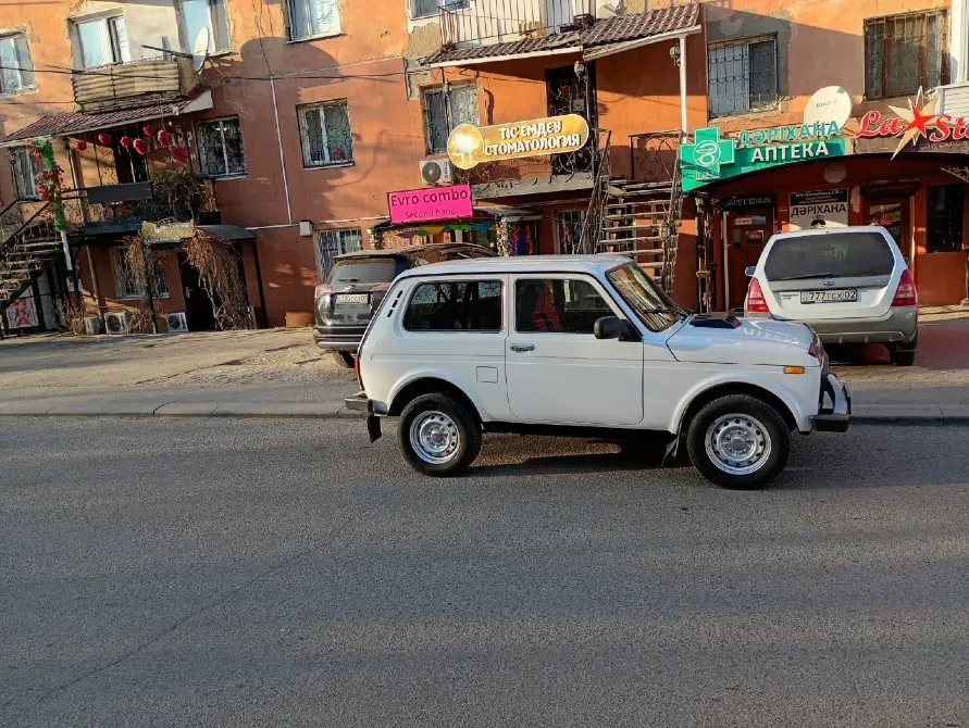 Автомобиль на улице с магазинами на заднем плане