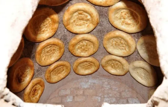 Хлеб, испекающийся в традиционной печи, с круглыми лепешками, уложенными по стенкам