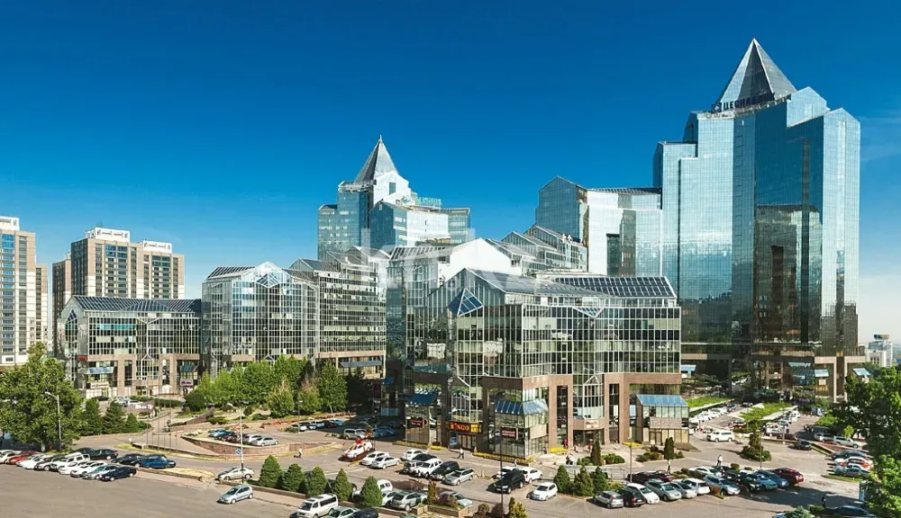 Қазіргі заманғы ғимараттар мен бизнес-орталықтар ашық көк аспан фонында қалада