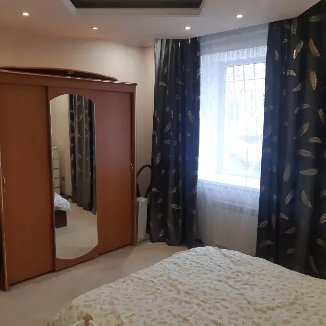 Спальня с зеркальным шкафом и окнами, покрытыми шторами