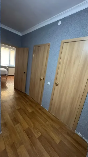 Бірнеше есігі бар ламинирленген ағаш еденімен коридор