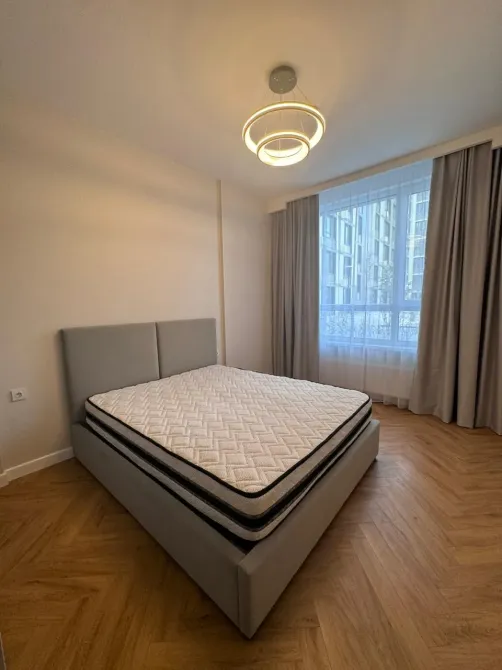 жайлы ұйықтау бөлмесі сұр төсекпен және үлкен терезелерімен