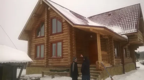 Дом из бревен на стадии строительства с окнами и крышей