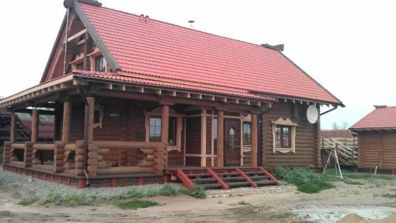 Дом из бревен на стадии строительства с окнами и крышей