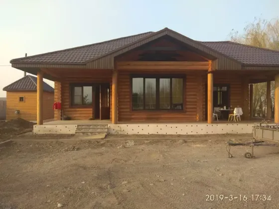 Деревянный дом с большими окнами и крышей из черепицы, окруженный зеленью