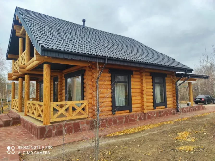 Табиғатпен қоршалған, верандасы және плиткамен жабылған屋шасы бар бөренелерден жасалған үй