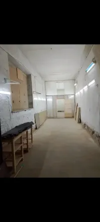 Бос бөлме, қабырғаға ілінген айна мен бұрышта қарапайым үстел